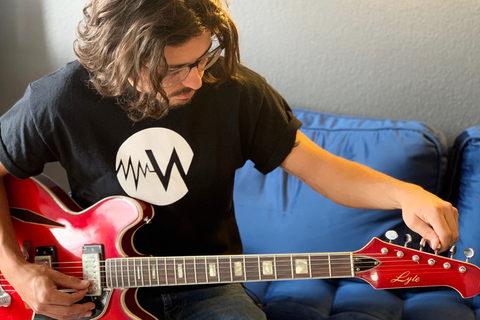 Man wearing cool T-shirt and tuning guitar